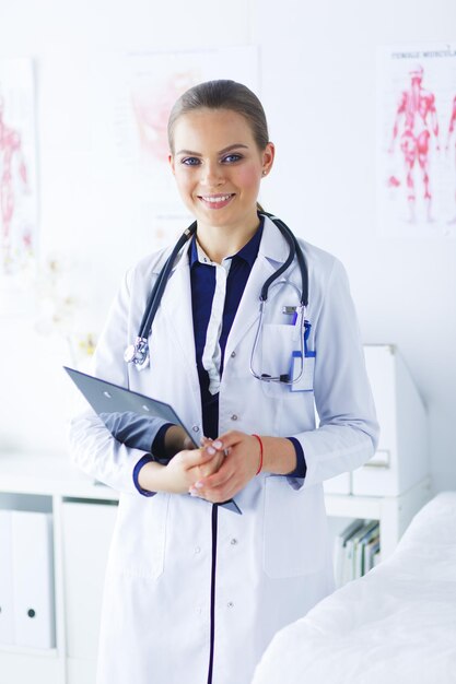 Doctora sonriente con una carpeta en uniforme de pie