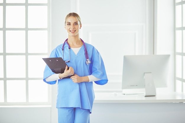 Doctora sonriente con una carpeta en uniforme de pie