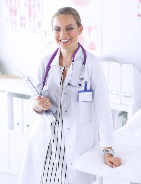 Doctora sonriente con una carpeta en uniforme de pie