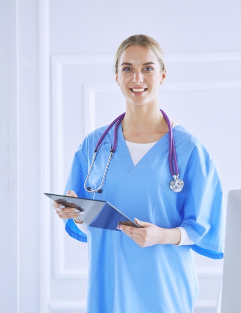 Doctora sonriente con una carpeta en uniforme de pie