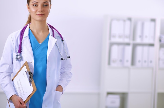 Doctora sonriente con una carpeta en uniforme de pie