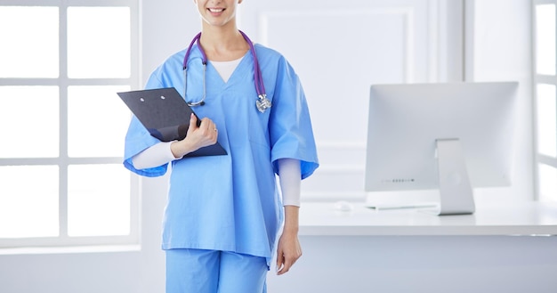 Doctora sonriente con una carpeta en uniforme de pie