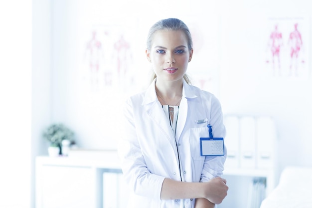 Doctora sonriente con un estetoscopio médico en uniforme de pie