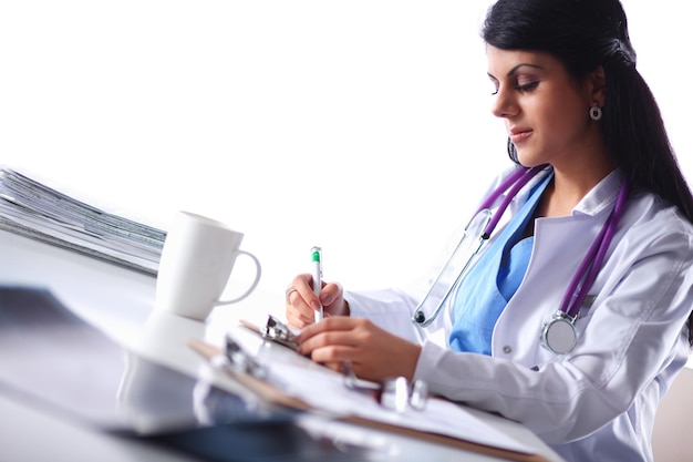 Doctora sonriente joven hermosa que se sienta en el escritorio.