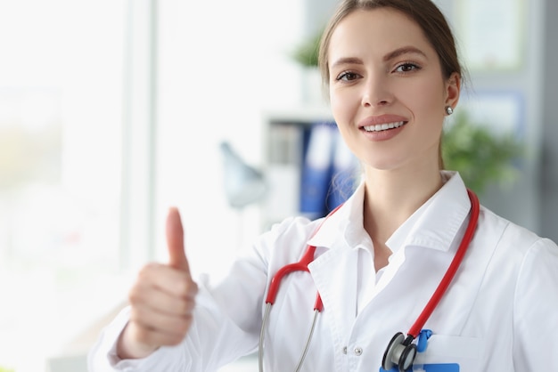 Doctora sonriente mostrando el pulgar hacia arriba en la clínica