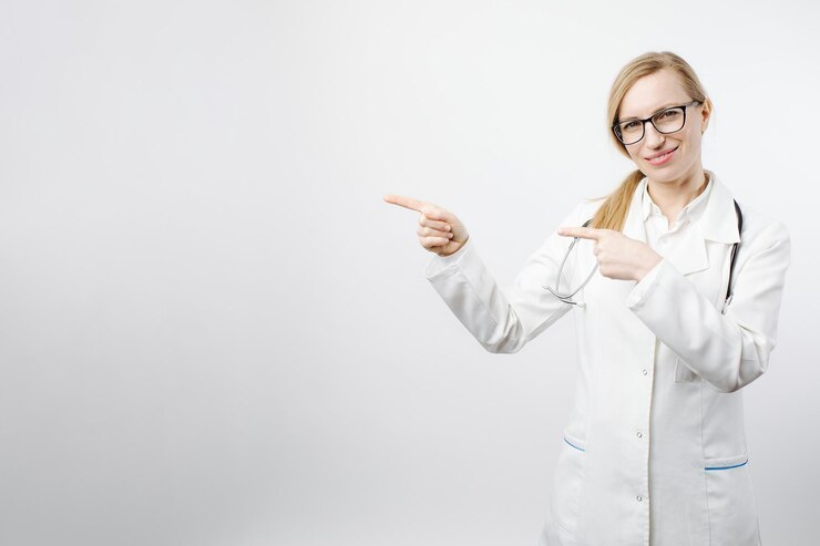 Doctora sonriente señalando con los dedos para copiar espacio