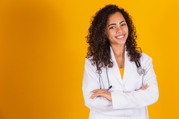 Doctora sonriente sobre fondo amarillo con los brazos cruzados