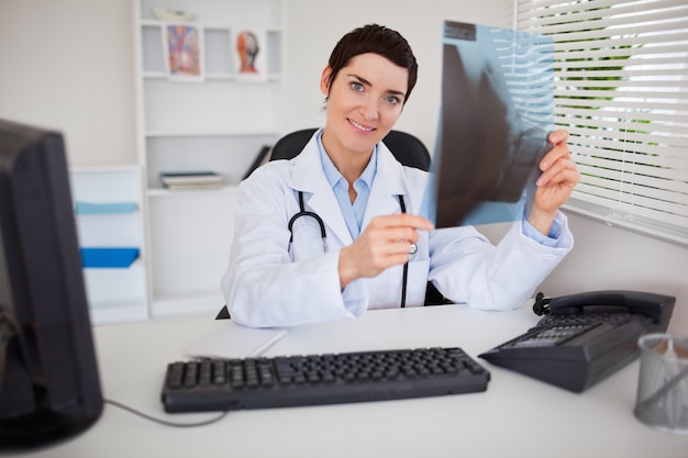 Doctora sonriente sosteniendo un conjunto de rayos x