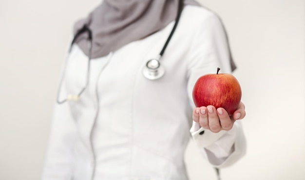 Doctora sosteniendo la manzana como símbolo de una alimentación saludable, enfoque selectivo