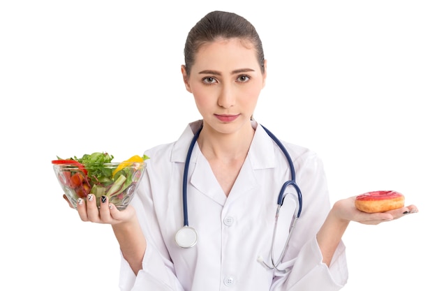 Doctora sosteniendo un plato con ensalada de verduras frescas y donut