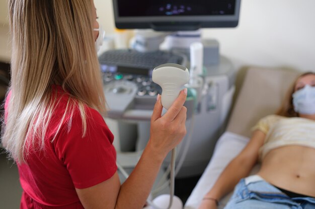 Doctora sosteniendo un transductor de ultrasonido frente al paciente en el diagnóstico clínico de