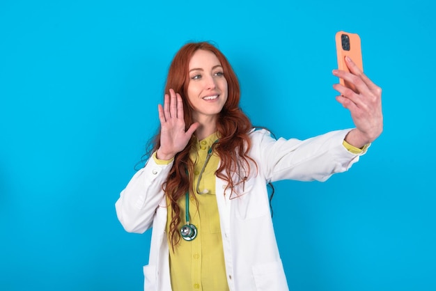 Foto la doctora sostiene un teléfono móvil moderno y hace una videollamada con su paciente