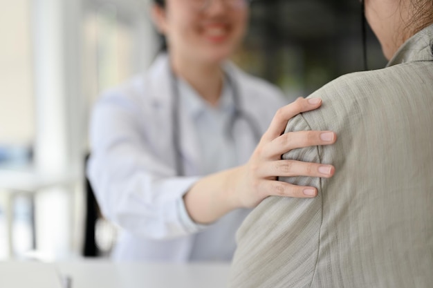 Una doctora tocando el hombro de un paciente apoyando y tranquilizando durante el chequeo médico