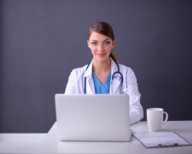 Foto doctora trabajando sentado sobre fondo gris