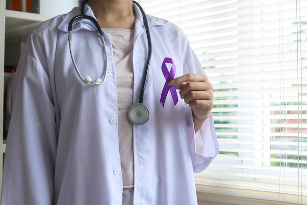 Doctora en uniforme blanco con cinta morada en la mano