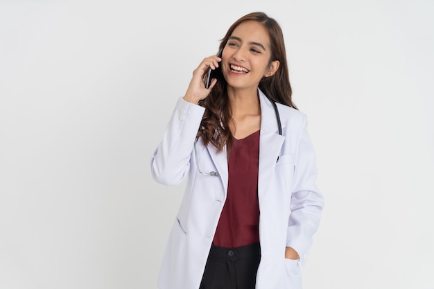 Una doctora con un uniforme blanco sonriendo mientras realiza una llamada telefónica