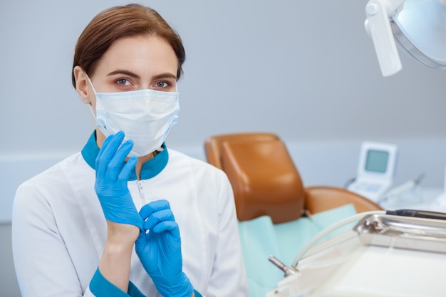 Doctora en uniforme con guantes médicos y máscara