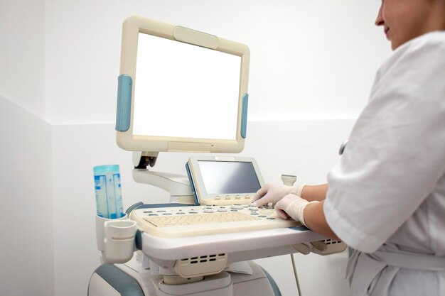 La doctora en uniforme usa una máquina de ultrasonido moderna con pantalla en blanco