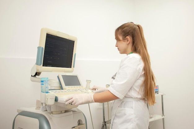 La doctora en uniforme usa una máquina de ultrasonido moderna con trabajos de enfermera de pantalla en blanco