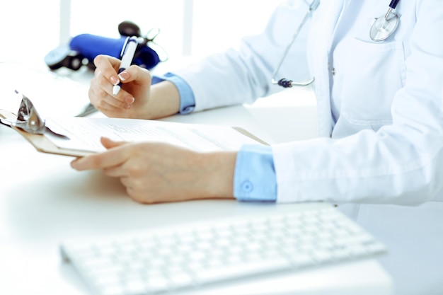 Foto doctora usando formulario médico en primer plano del portapapeles. trabajo médico en hospital o clínica. concepto de salud, seguros y medicina