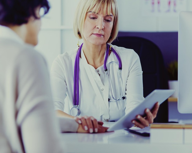 Doctora usando tableta digital hablando con pacientes