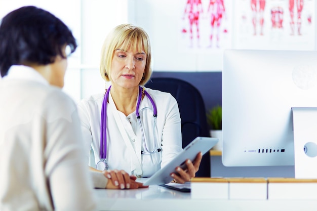 Doctora usando tableta digital hablando con pacientes