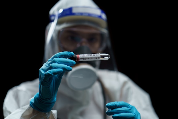 Doctora vistiendo trajes de materiales peligrosos con kit de recogida de hisopos en el laboratorio.