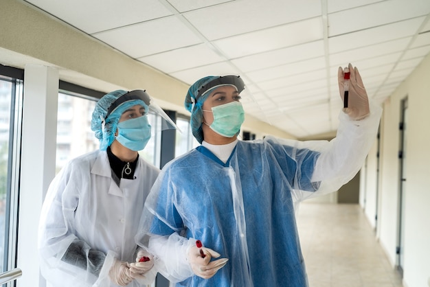 Doctoras con ropa protectora sostiene un tubo de ensayo con muestra de sangre para el coronavirus