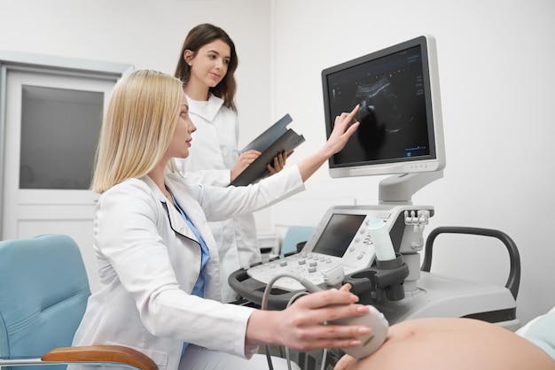 Doctores haciendo diagnóstico de ultrasonido de mujer embarazada.