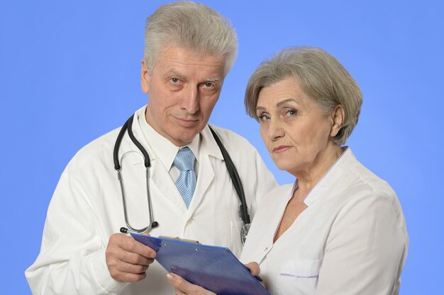 Doctores de mujer y hombre posando contra azul