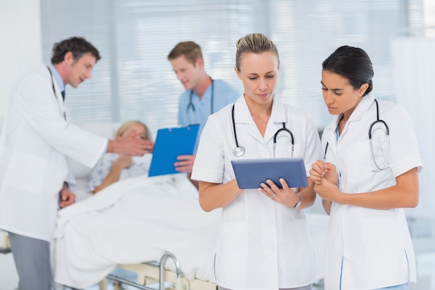 Doctores que miran el tablero mientras que sus colegas hablan con el paciente
