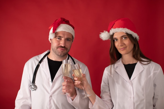 Doctores con sombreros de Santa Claus animando con copas de champán