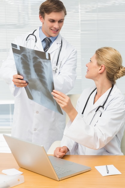 Doctores sonrientes que examinan una radiografía juntos