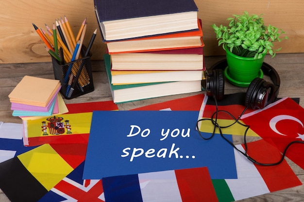 Foto documento conceptual de aprendizaje de idiomas con texto ¿hablas banderas libros auriculares lápices sobre fondo de madera