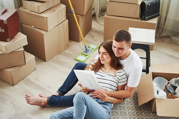 Documento de lectura. Pareja joven alegre en su nuevo apartamento. Concepción de mudanza.