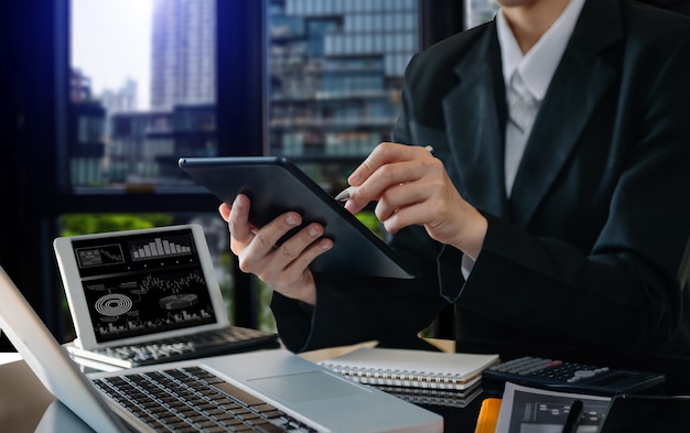 Documentos comerciais na mesa do escritório com telefone inteligente e tablet digital e gráfico financeiro e mulher trabalhando