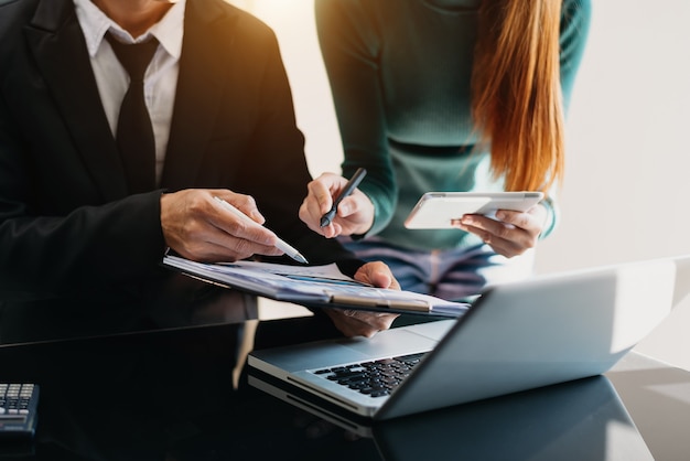 Documentos de negócios na mesa do escritório com smartphone e calculadora digital tablet e gráfico de negócios com diagrama de rede social e dois colegas discutindo dados trabalhando no escritório