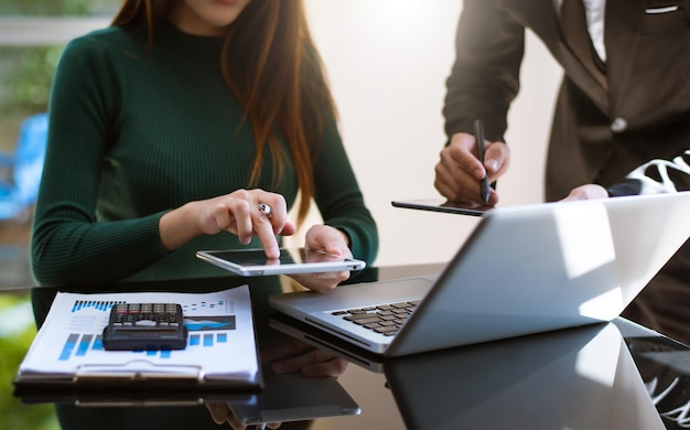 Documentos de negócios na mesa do escritório com smartphone e portátil e dois colegas discutindo dados ao fundo
