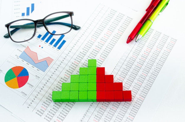 Documentos financeiros, com cubos verdes dispostos em um gráfico de colunas como um conceito para receitas, despesas ou receitas