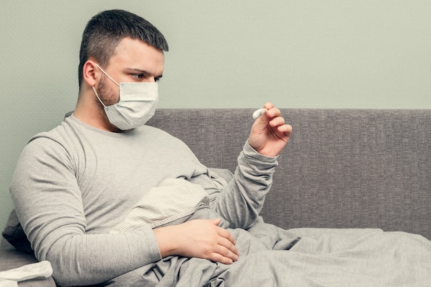 Foto doença. torça em casa. um jovem está doente, é tratado em casa. funde o nariz em um guardanapo, coriza. infecção, epidemia, portador de bacilo.