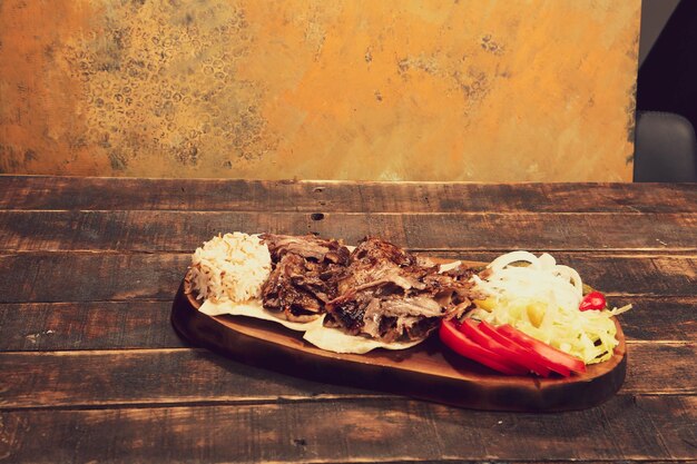 Döner liegt auf dem Schneidebrett Shawarma mit Fleischzwiebelsalat liegt auf einem dunklen alten Holz