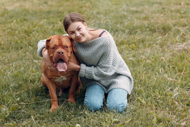 Dogue de bordeaux ou mastiff francês com jovem no parque ao ar livre.