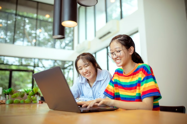 Dois adolescentes asiáticos trabalhando em um laptop