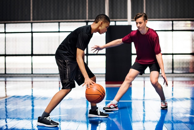 Dois adolescentes jogando basquete juntos na quadra