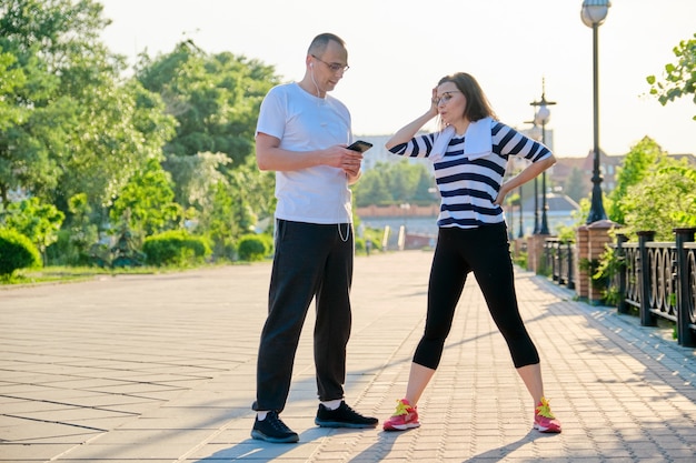 Dois adultos descansando, conversando após os exercícios esportivos, correndo no parque. Estilo de vida ativo e saudável, esporte, condicionamento físico em pessoas de meia-idade