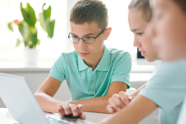 Dois alunos concentrados em seus trabalhos escolares enquanto estão sentados em frente a um laptop e olhando informações on-line