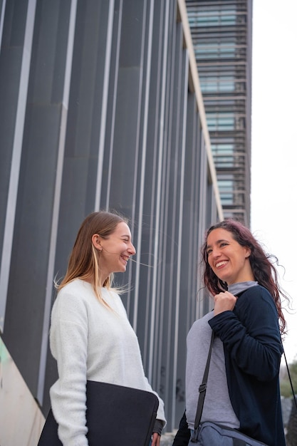 Dois alunos conversando e sorrindo do lado de fora de um centro de estúdio Estudantes adultos de estudo à distância