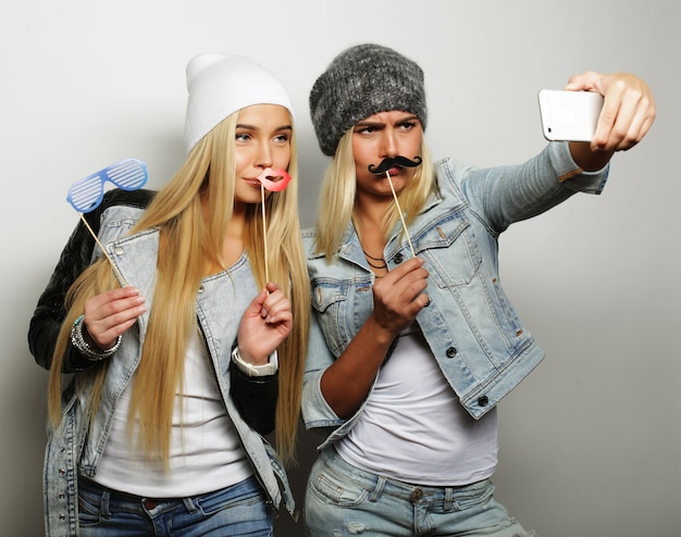 Foto dois amigos adolescentes em roupa hipster fazem selfie em um telefone.