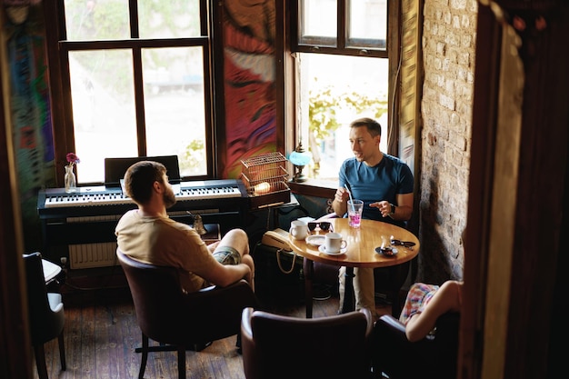 Dois amigos adultos do sexo masculino sentados e conversando no café