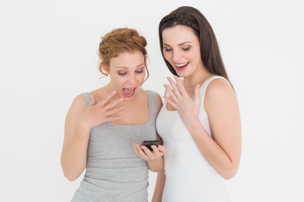 Dois amigos alegres que olham para celular